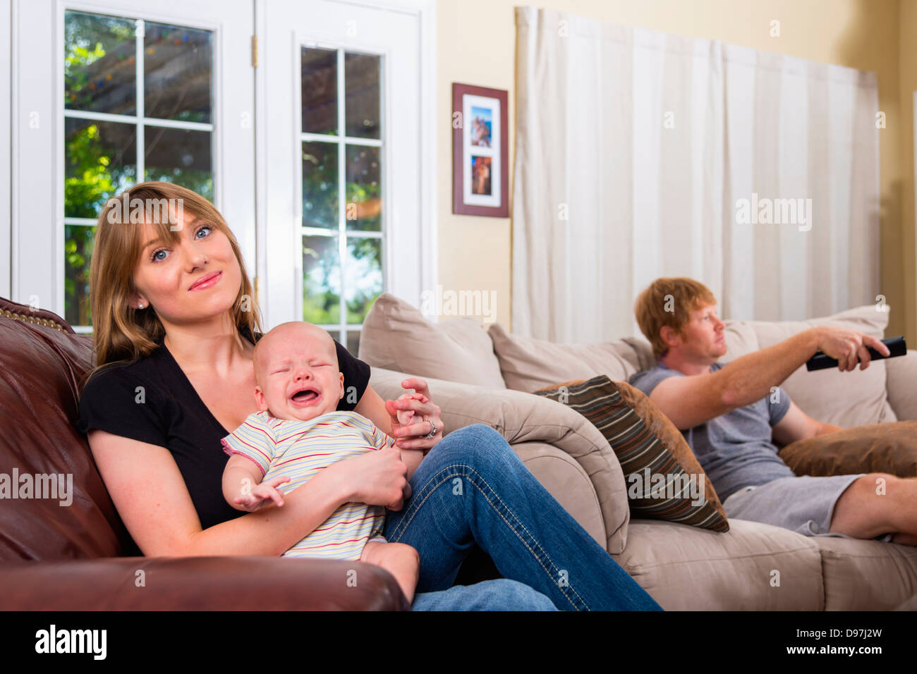 Junge Eltern - männlichen kaukasischen 34, Weiblich kaukasischen 20 männlichen kaukasischen Baby 2 Monate im Wohnzimmer vor dem Fernseher sitzen Stockfoto