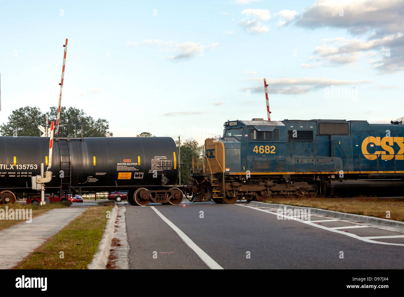 CSX Motor 4682 ziehen einen Güterzug, einschließlich eine schwarze Wanne Auto durch einen Bahnübergang in Hawthorne, Florida. Stockfoto