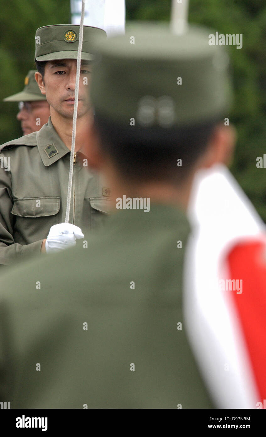 Mitglieder des Japan Ground Self-Defense Forces (GSDF) erhöhen die japanische Flagge vor einem Feuer Übung in Japan Stockfoto