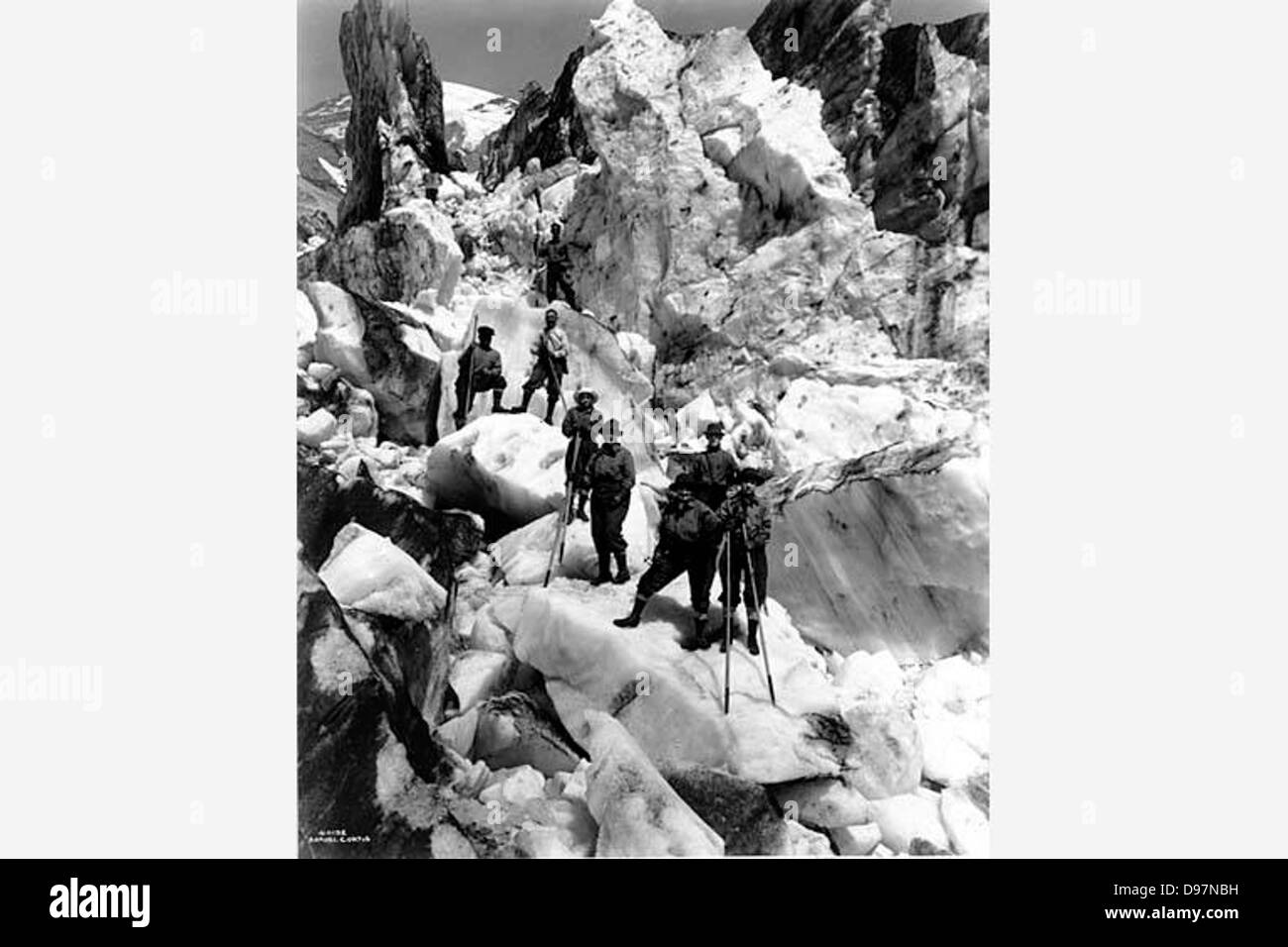 Ein Foto von Asahel Curtis, das eine Kletterparty zeigt, die ein Eisfeld durchquert. Das Bild zeigt Bergsteiger, die sich mit dem Eisklettern beschäftigen, und veranschaulicht die Herausforderungen und Techniken der Aktivität. Stockfoto