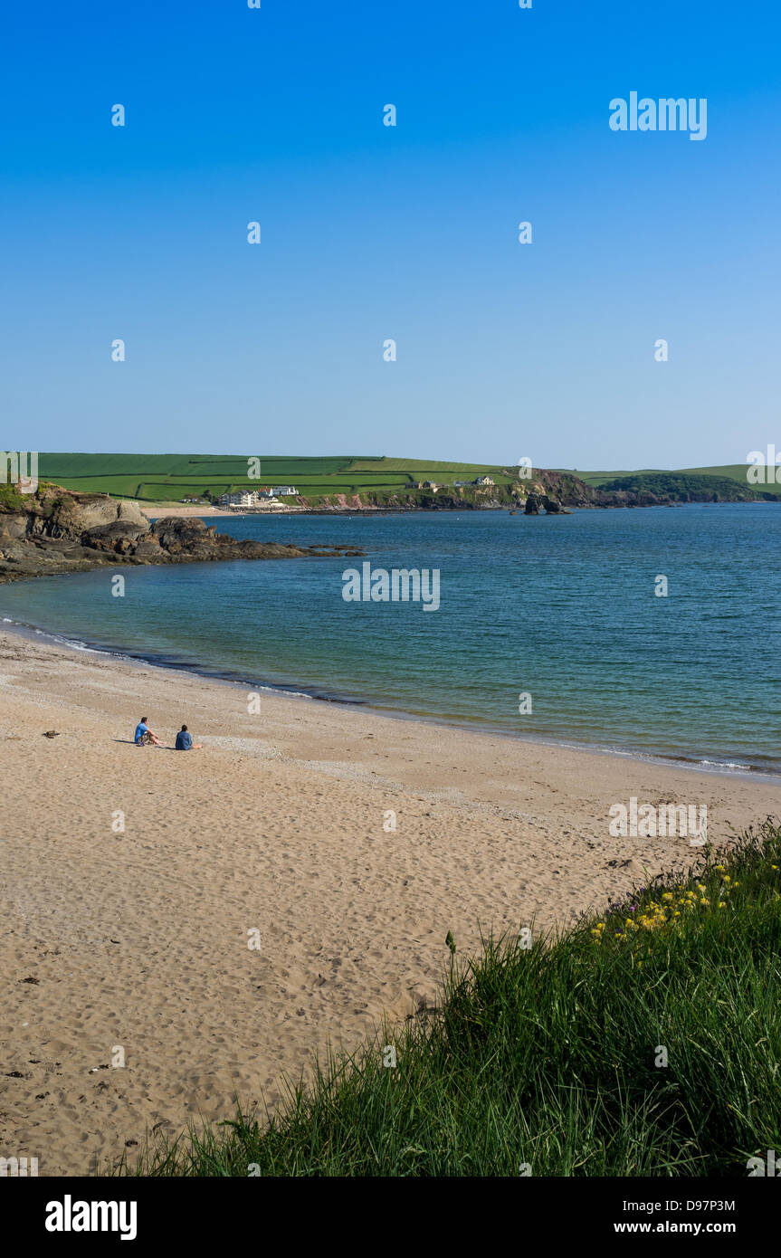 Thurlestone, Devon, UK. 3. Juni 2013. Ein paar sitzen und entspannen Sie sich auf Thurlestone Strand mit Blick auf die Bucht und den Thurlestone Felsen. Stockfoto