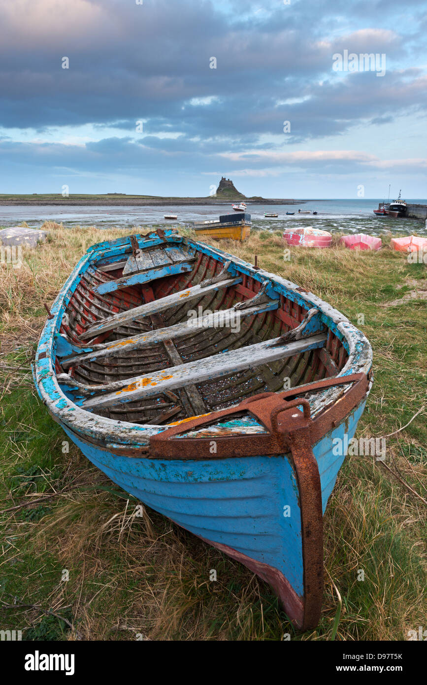 Altes Fischerboot zog am Ufer auf der Heiligen Insel, mit der Burg über die Bucht, Lindisfarne, Northumberland. Stockfoto