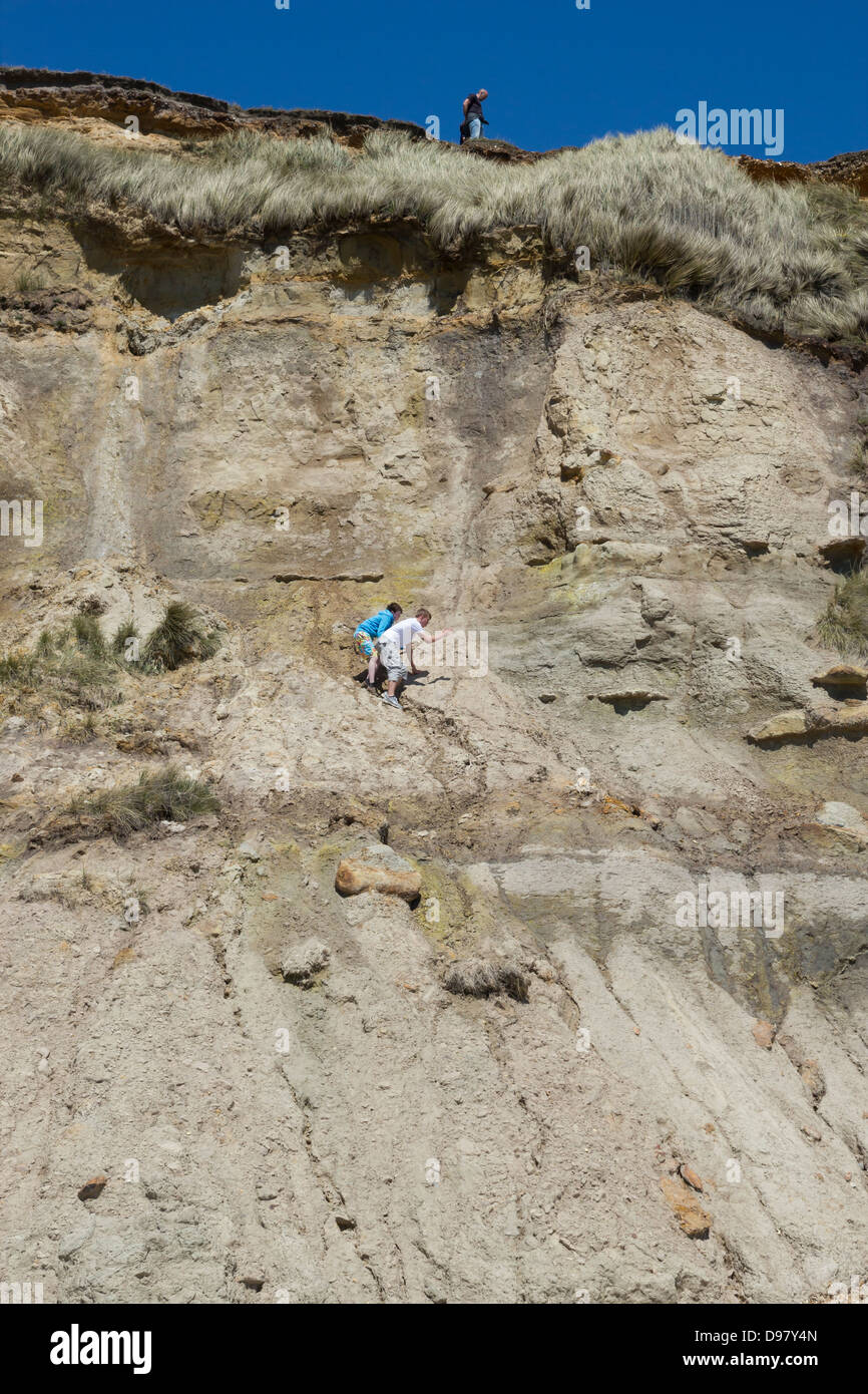 2 Jungs zwei jungen kriechen / Klettern / absteigend auf prekäre instabiler Klippe mit Erwachsenen auf Klippe Stockfoto