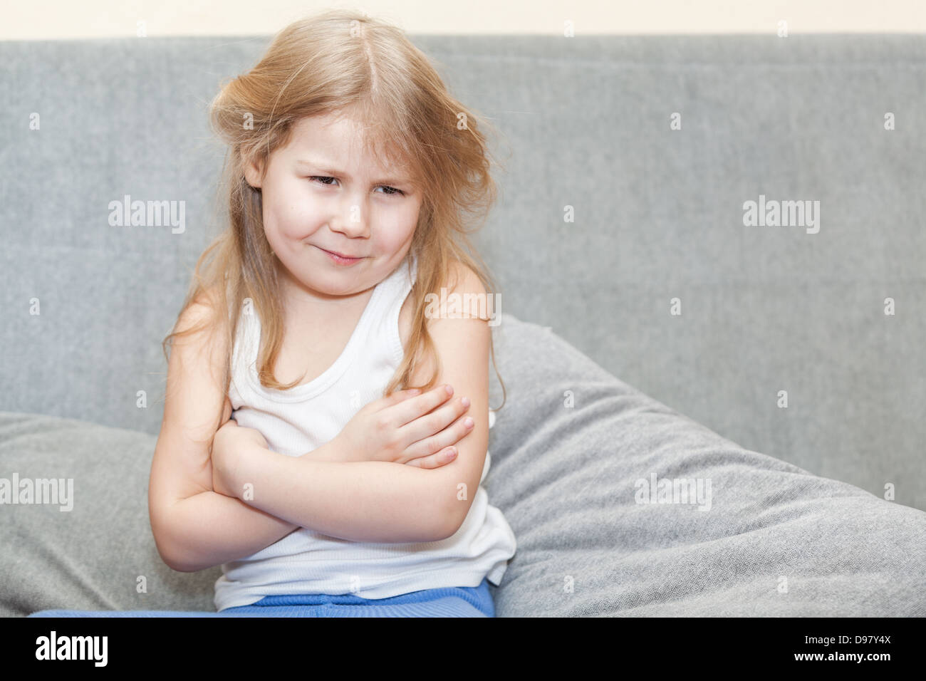 Die Mädchen sitzen auf der Couch mit ihren Händen auf seiner Brust gefaltet Gefühle verletzen Stockfoto