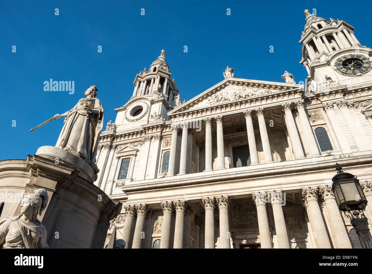 Queen Victoria Statue St Paul's Cathedral London England // LONDON, England – Eine Statue von Königin Victoria steht prominent vor der St Paul's Cathedral und zeigt den Monarchen in voller königlicher Kleidung mit ihren königlichen Regalen. Die Statue wurde vom Bildhauer Thomas Brock geschaffen und 1886 zum Gedenken an das Goldene Jubiläum der Königin enthüllt. Sie zeigt Victoria mit einem vergoldeten Zepter und der Kugel des Herrschers, traditionelle Symbole der königlichen Autorität. Das Denkmal zeigt vier allegorische Figuren an seiner Basis, die Gerechtigkeit, Wahrheit, Mutterschaft und Frieden darstellen – Tugenden, die mit viktorianischen Idealen assoziiert sind. St. Paul's CA Stockfoto