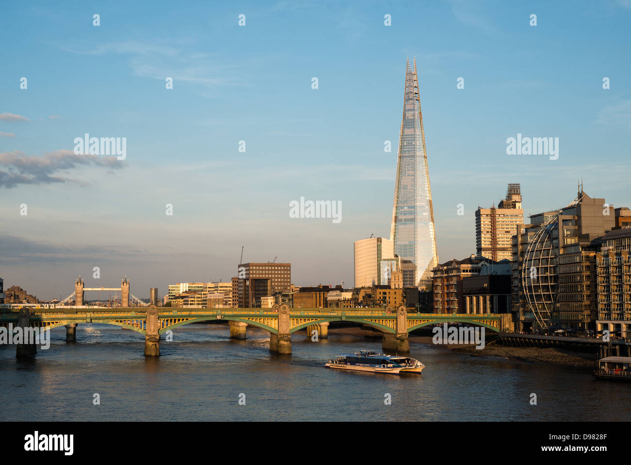 LONDON, Großbritannien – Ein Panoramablick auf die Londoner Skyline von der Millennium Bridge nach Osten. Die Southwark Bridge überspannt die Themse im Vordergrund, während die berühmte Tower Bridge in der Ferne links zu sehen ist. Das Shard, Londons höchstes Gebäude, dominiert die Skyline mit seiner charakteristischen kantigen Form. Stockfoto