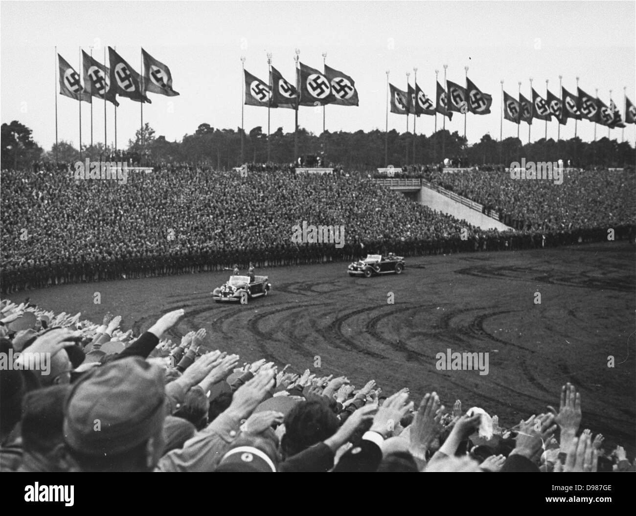 Adolf Hitler begrüßt die Zuschauer bei seiner Ankunft auf dem Zeppelinfeld in Nürnberg für den Reichsparteitag (Reich Party Tag) Zeremonien. Stockfoto