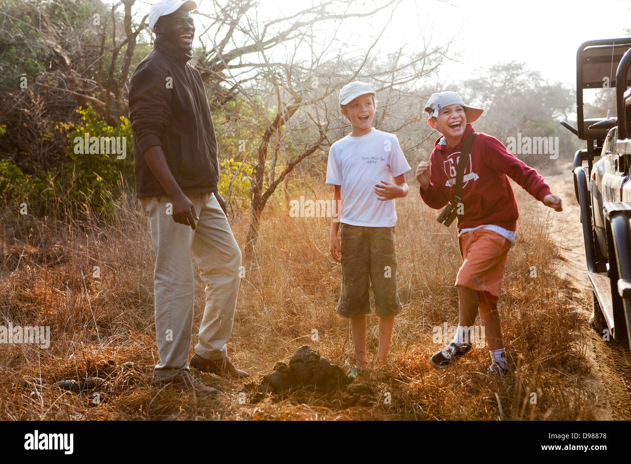 Jungen studieren Rhino Dung mit ihren Tracker, Bernard in das Game Reserve. Robin hatte nur Verkostung das Dung überlistet. Stockfoto
