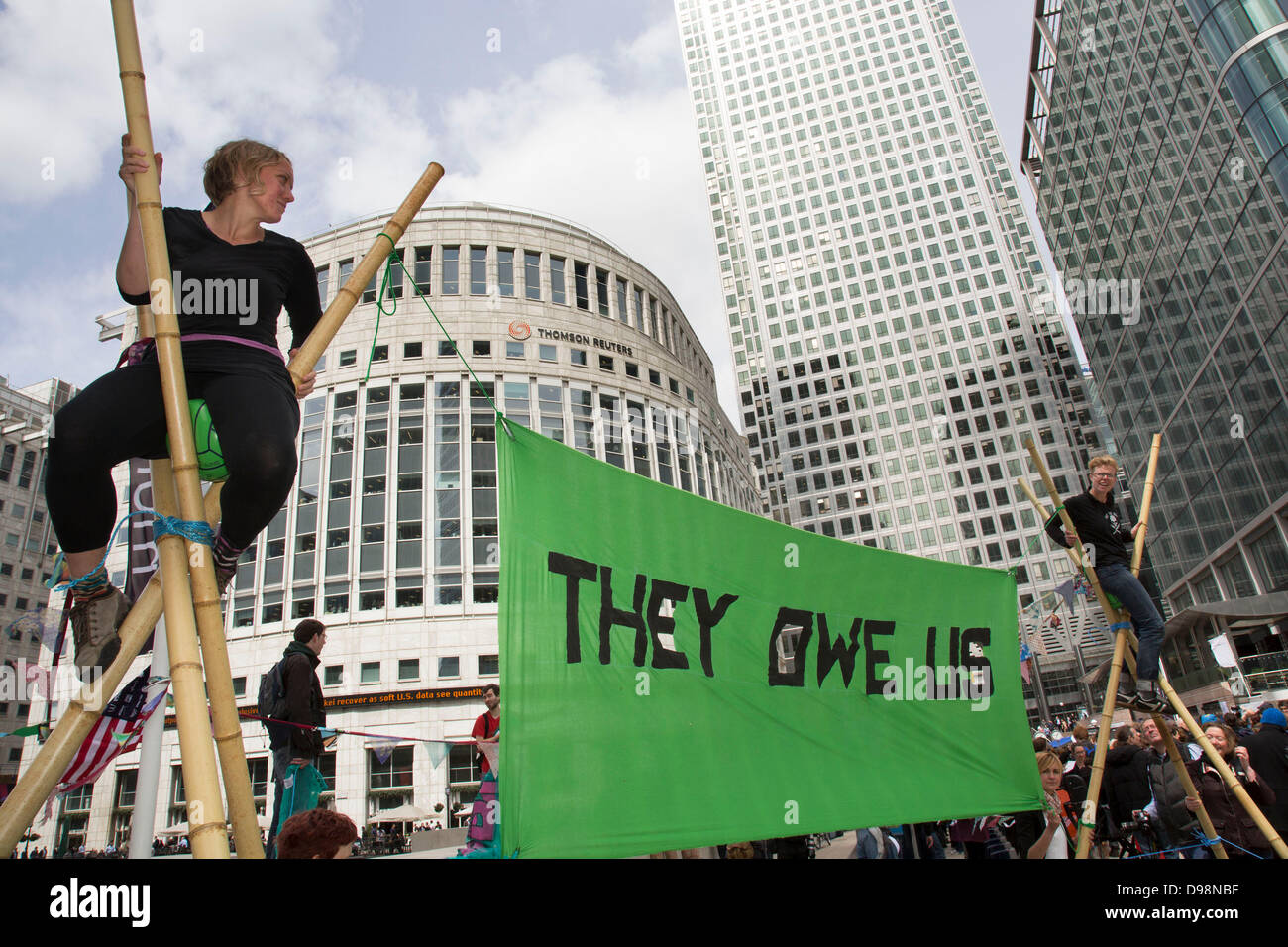 Anti-G8-Demonstranten auf Stative in der Canary Wharf Business-Viertel von London. Teil eines Protestes genannt "sie Schulden uns" dessen Punkt ist, dass während reichen G8-Länder gerecht zu werden, es sind die Armen, die immer noch bezahlen. Stockfoto