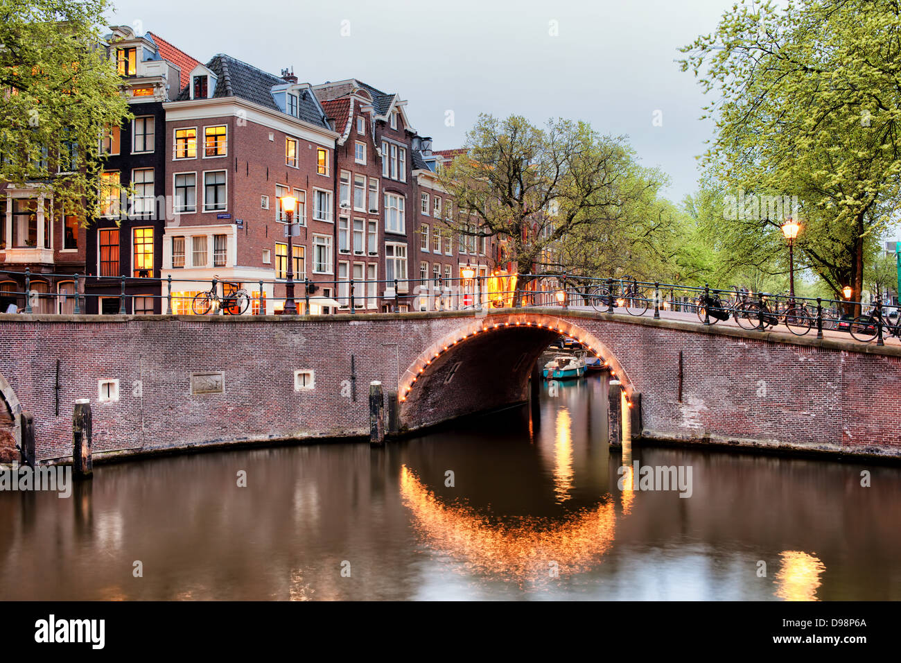 Kanal-Brücke-Beleuchtung und Häuser am Abend in der Stadt Amsterdam, Niederlande, Nord-Holland Provinz. Stockfoto