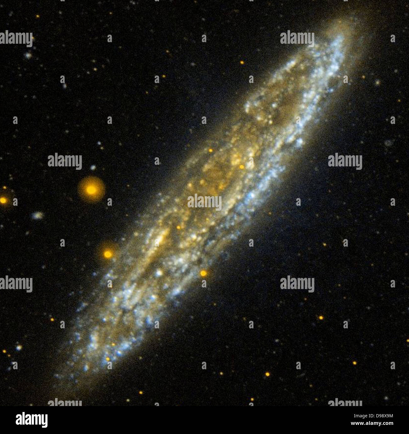 Silver Dollar Galaxy: NGC 253 nur 10 Millionen Lichtjahren im südlichen Sternbild Bildhauer, der Silver Dollar Galaxie, NGC 253, ist eine der hellsten Spiralgalaxien in den Nachthimmel. In dieser Kante Blick von der NASA Galaxy Evolution Explorer, die Fetzen von Blau stellen relativ staubfreien Bereichen der Galaxie, die aktiv Sterne bilden. Bereiche der Galaxie mit einem weichen goldenen Glanz zeigen Regionen, in denen die weit - Ultraviolett ist stark durch Staub verdeckt werden. Stockfoto