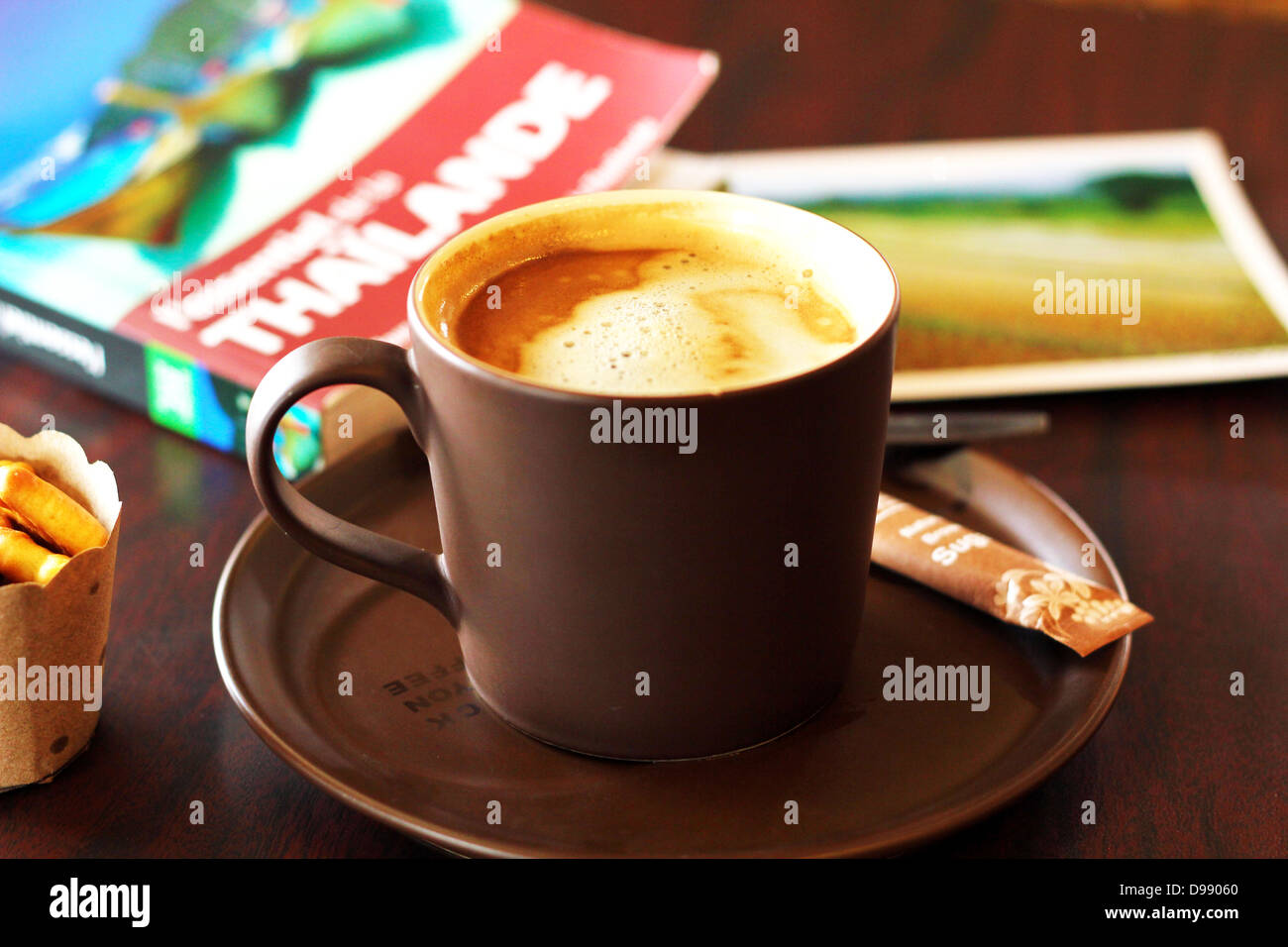 Tasse mit Kaffee mit Thailand Reisen Reiseführer und eine Postkarte auf dem Hintergrund in der Coffee House in Chiang Mai, Thailand Stockfoto