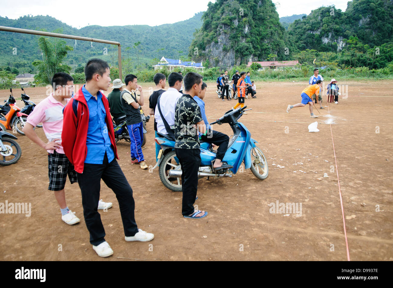 VIENG XAI, Laos - Hmong Studenten in Vieng Xai im Nordosten Laos spielen ein traditionelles Spiel der tujlub, die spinnen Holz- Tops mit string und Sticks geschleudert. Während man oben noch dreht, eine andere Person versucht, Sie zu schlagen. Wenn Sie sie nicht schlagen, Sie sind heraus. Wenn sie es tun, der Sieger ist derjenige, dessen top Spinning die längste geht weiter. Die Studenten an der Linken sind Zuschauer, während einer der Teilnehmer Mitte rechts schleudert seine Top. Stockfoto