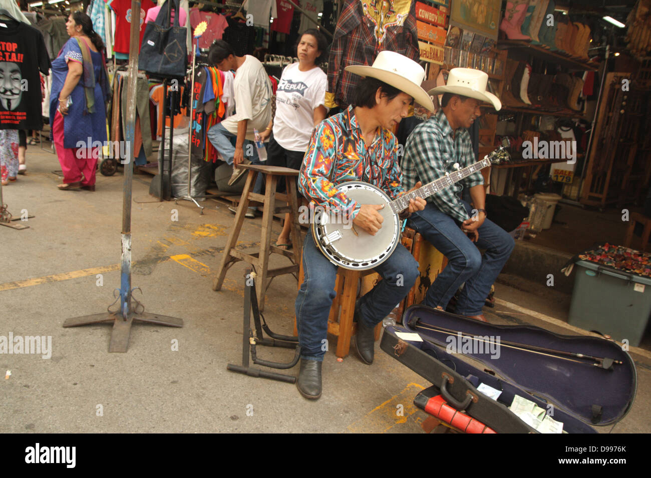 Cowboy-Musiker spielt Banjo in der Nähe einer westlichen Tuch Shop am Chatuchak Weekend Market, Thailand Stockfoto