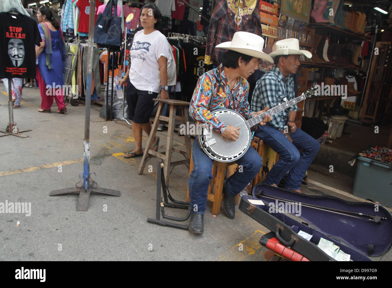 Cowboy-Musiker spielt Banjo in der Nähe einer westlichen Tuch Shop am Chatuchak Weekend Market, Thailand Stockfoto
