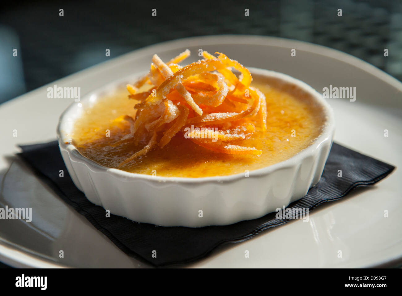 einzelne Portion Creme Brulee garniert mit orange Stockfoto