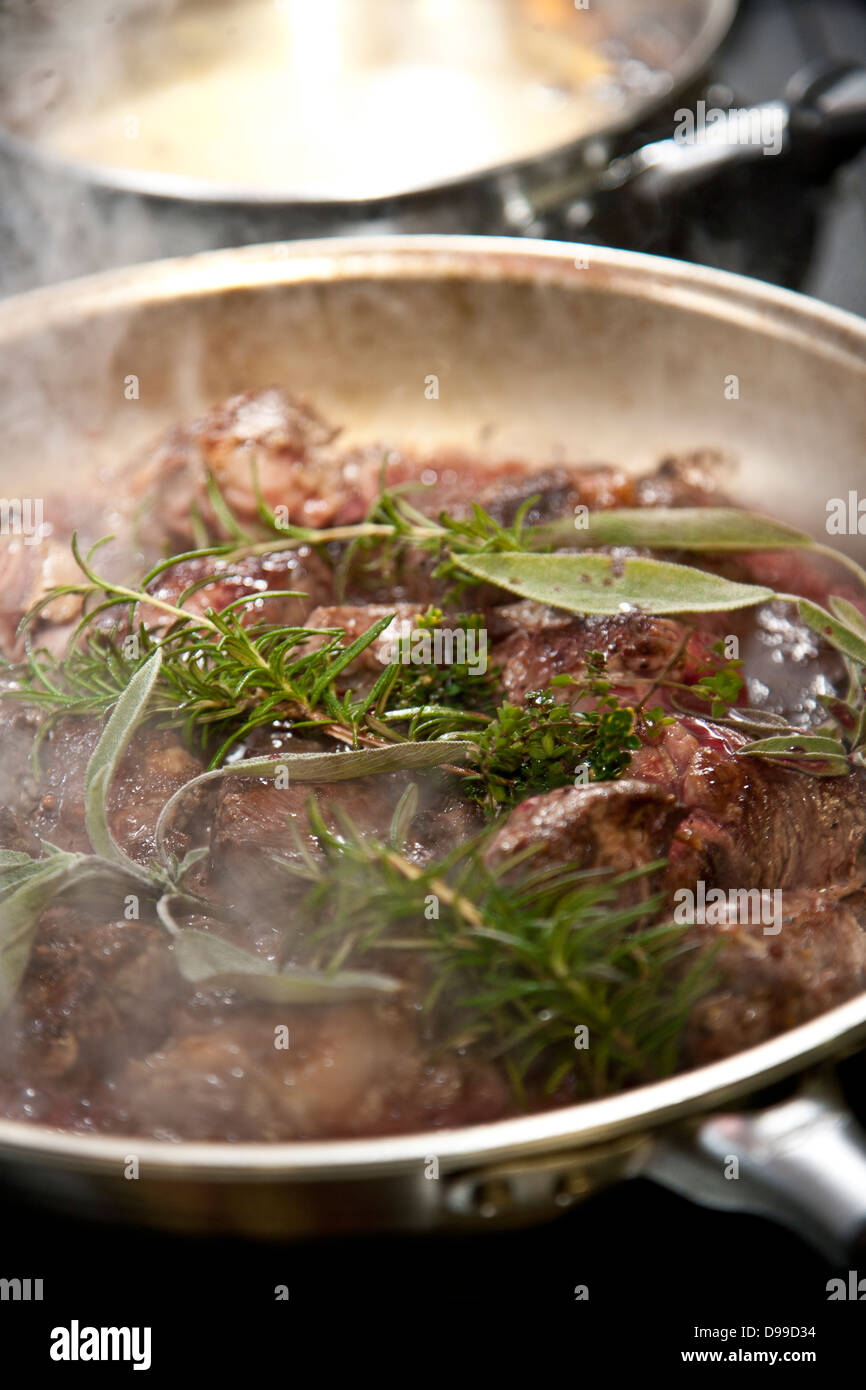 Geschmortes Fleisch in einer Pfanne mit frischen Kräutern und Rotwein Stockfoto