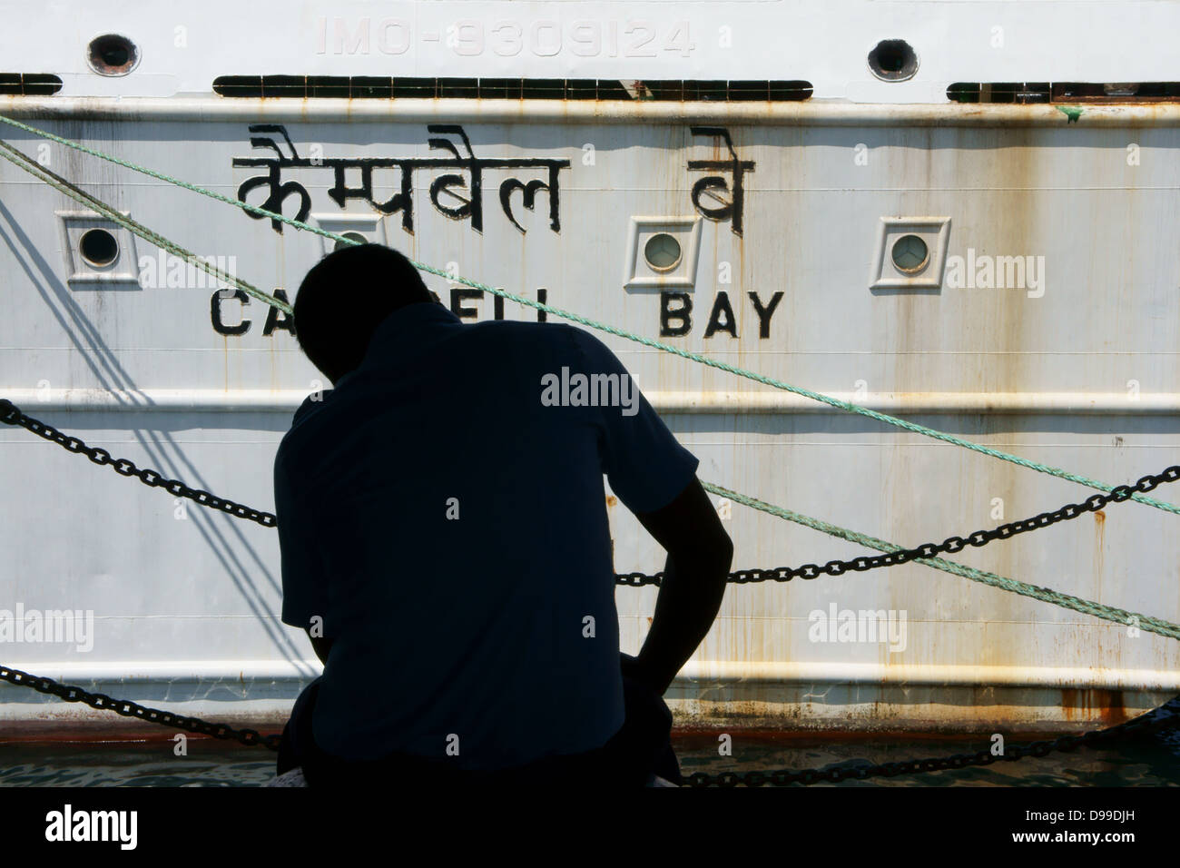 Silhouette eines Mannes mit einem Schiff im Hintergrund sitzen Stockfoto