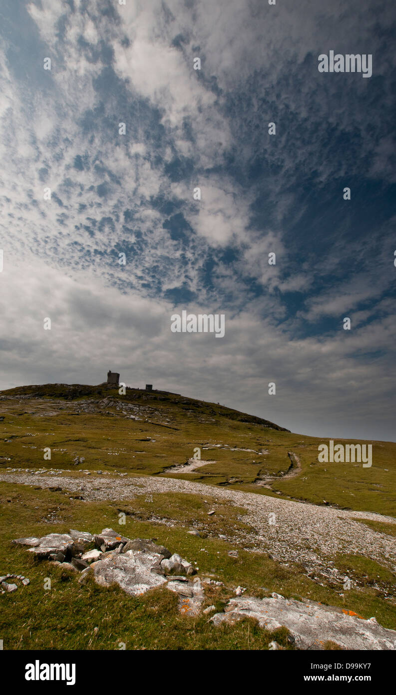 Malin Head Tower, County Donegal, am fernen Horizont mit Cirruswolken im Himmel und felsigen Vordergrund. Stockfoto