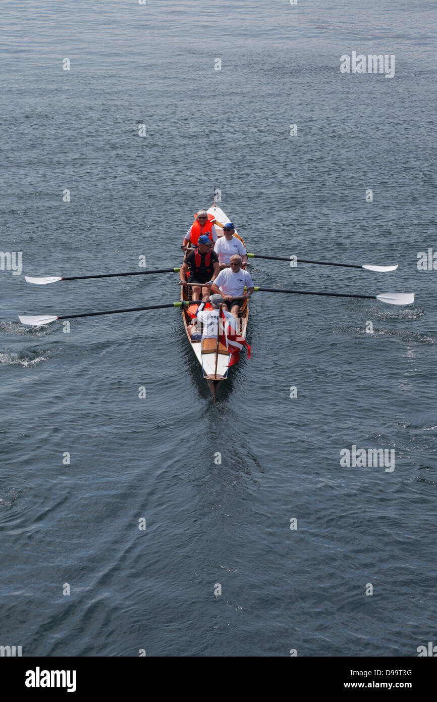 A Vierer Inrigger-Ruderboot Club mit einer Besatzung von Korsør Rowing Club Rudern durch den Hafen von Kopenhagen, Dänemark. Stockfoto