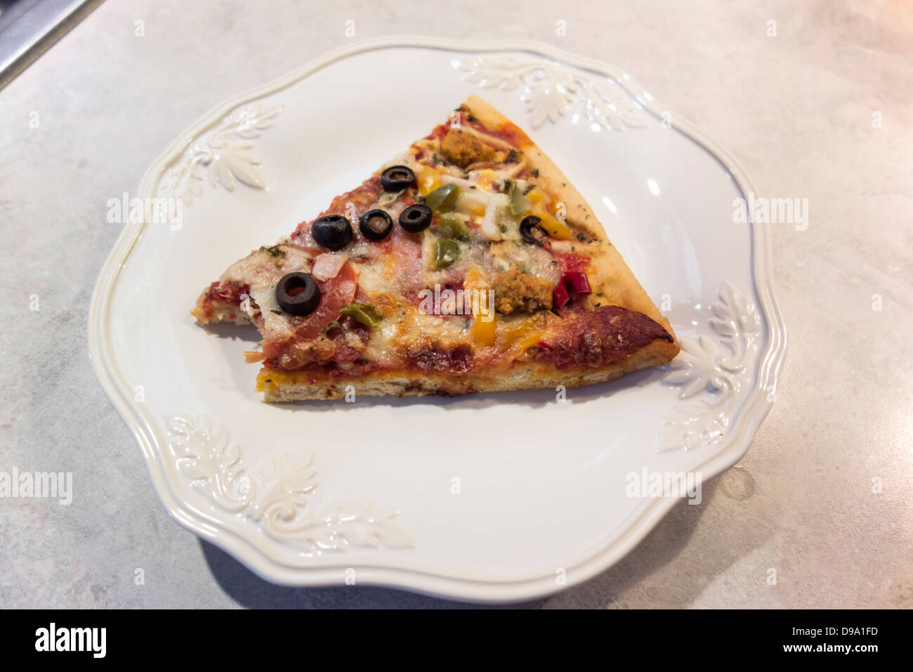 Ein Slize oberste Pizza mit einem Biss herausgenommen, auf einem weißen Teller. Hautnah. USA. Stockfoto