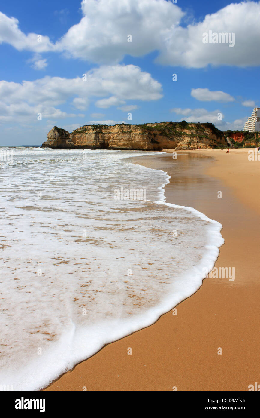 Wellen entlang der goldenen Sandstrand und ockerfarbenen Klippen von Praia da Rocha an der Algarve, Portugal Stockfoto