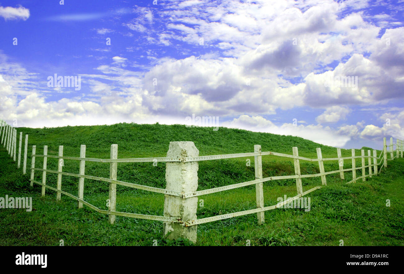 Weißes Metall Zaun mit einer grünen Wiese und blauer Himmel Stockfoto