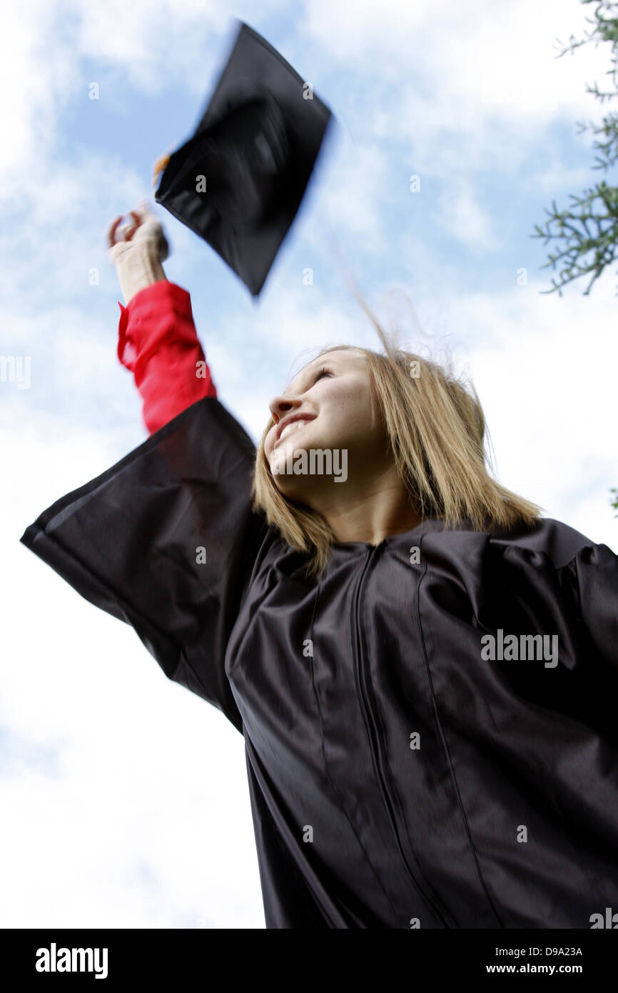Eine junge Frau, die Studium eine Graduierung-Kappe in die Luft werfen Stockfoto