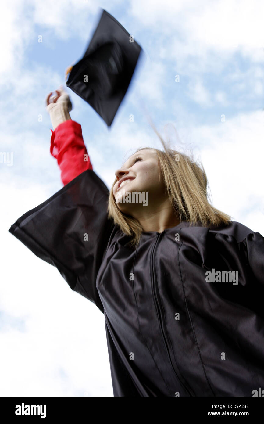 Eine junge Frau, die Studium eine Graduierung-Kappe in die Luft werfen Stockfoto