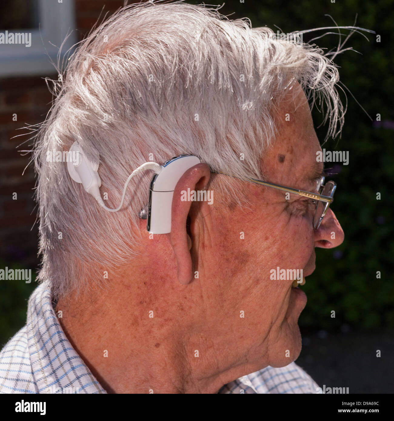 Eine Nahaufnahme von einem älteren Mann mit seinem Hörgerät Cochlea-Implantat in England, Großbritannien, Vereinigtes Königreich Stockfoto