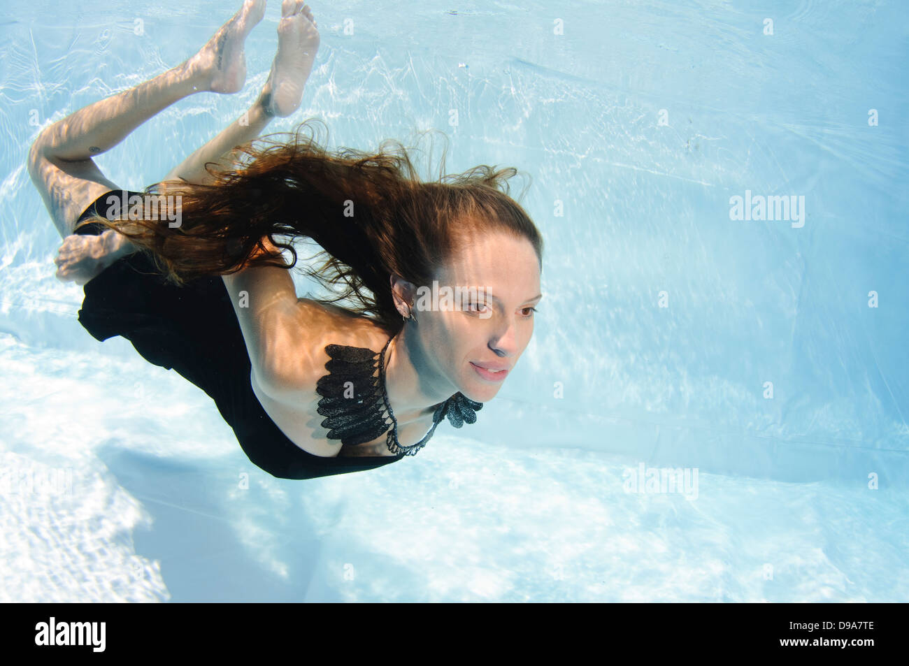 Eine junge Frau im Abendkleid schwimmt Unterwasser Model-Release verfügbar Stockfoto