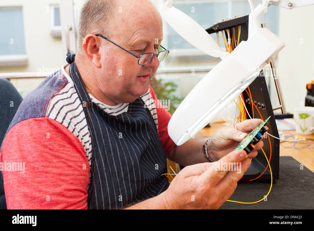 leitender Techniker prüfen elektrische Leiterplatte unter elektronische Lupe Stockfoto