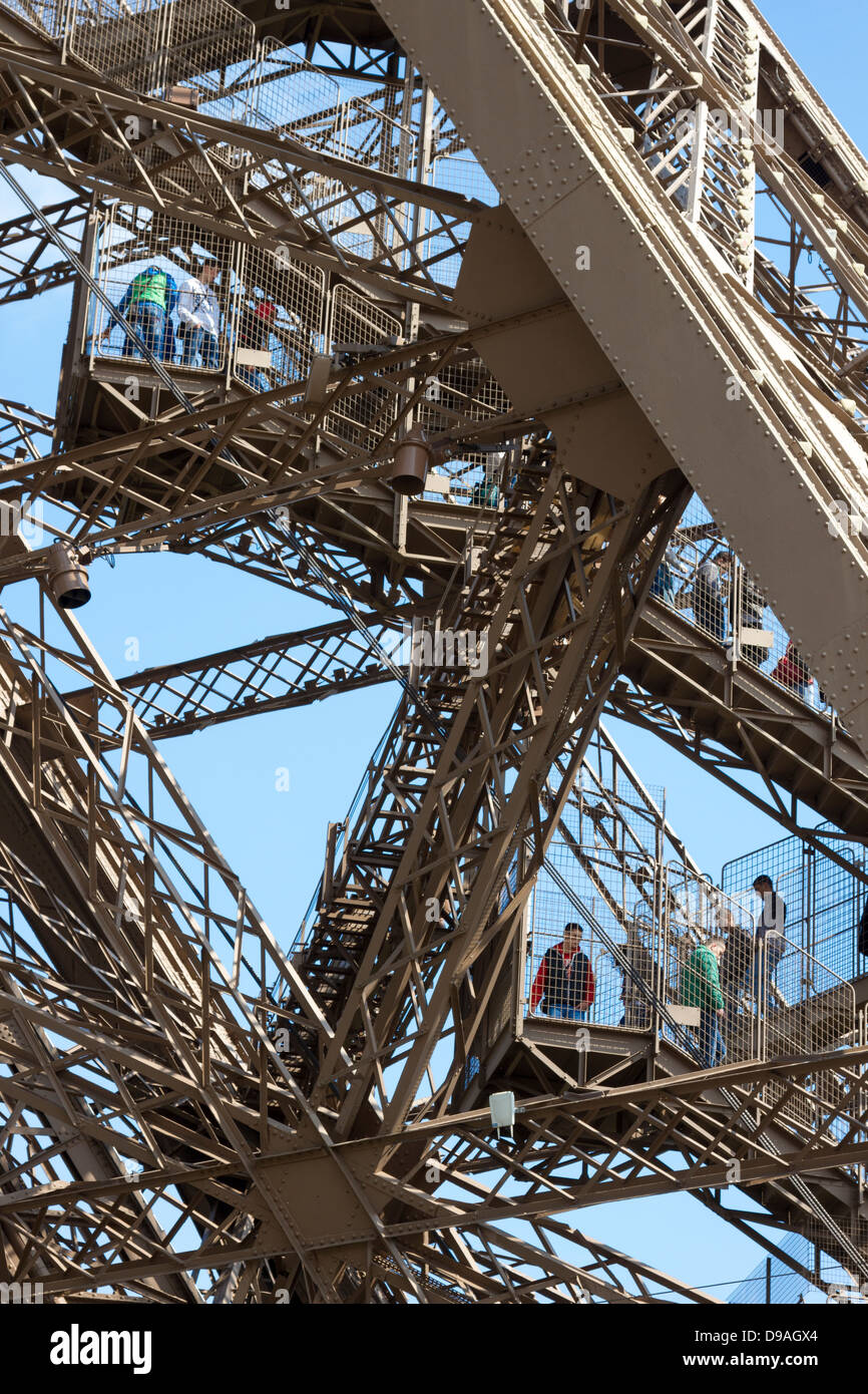 Touristen zu Fuß hinunter in Einzelschritten Komplex Gitter Eisenträger Abstieg aus der ersten Ebene des Eiffelturms in Paris Stockfoto