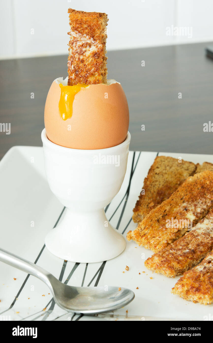Laufende gekochtes Ei und Toast Soldaten Stockfoto