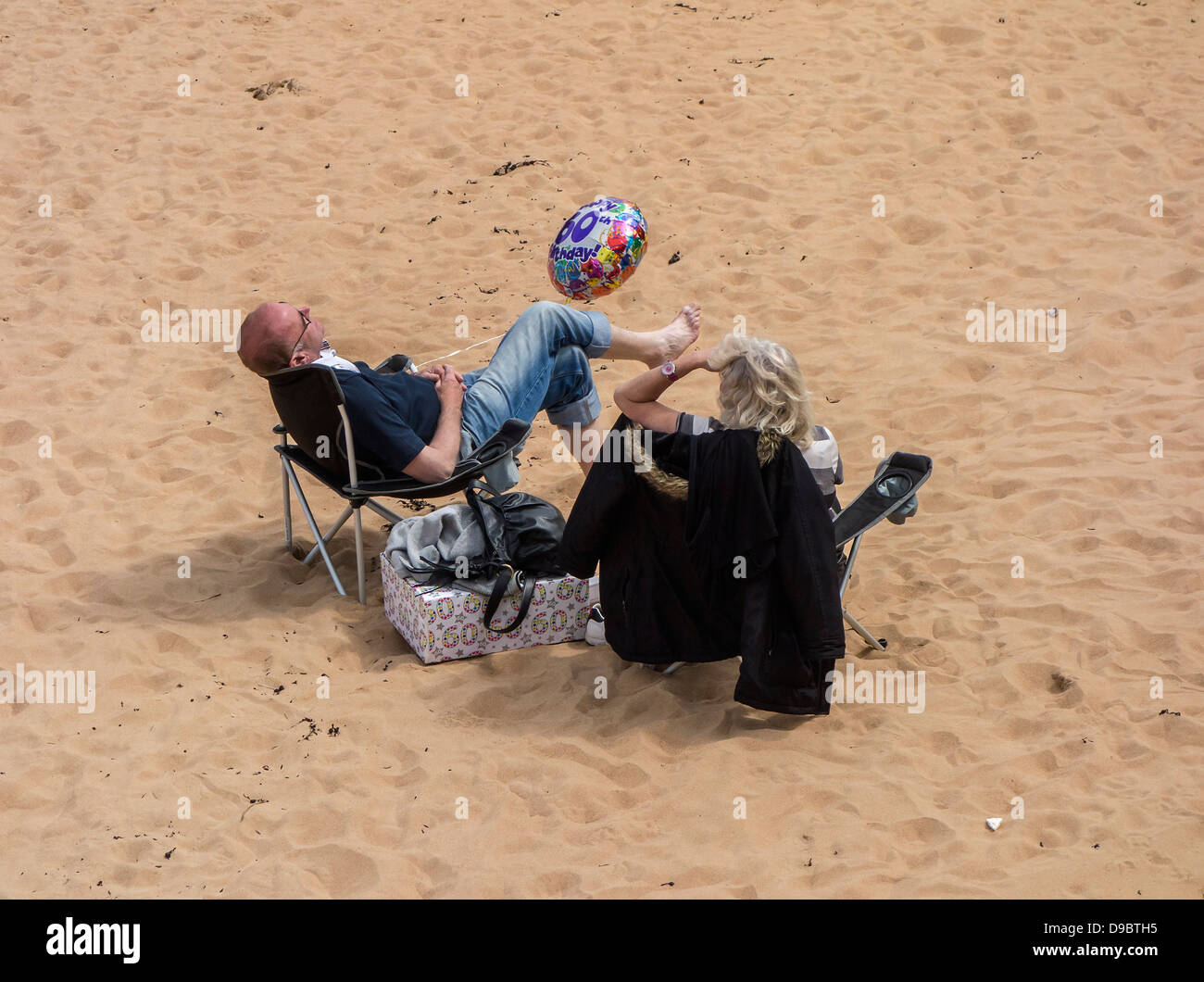 Jersey, Strand, Paar entspannende, sitzend mit Ballon, feiert 60. Geburtstag, Channel Islands Stockfoto