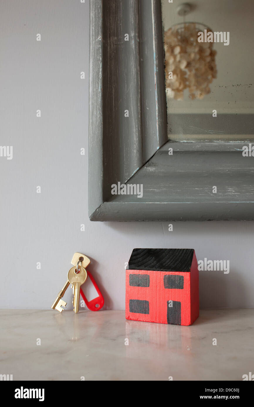 Modell des Hauses und Schlüssel auf Kaminsims Stockfoto