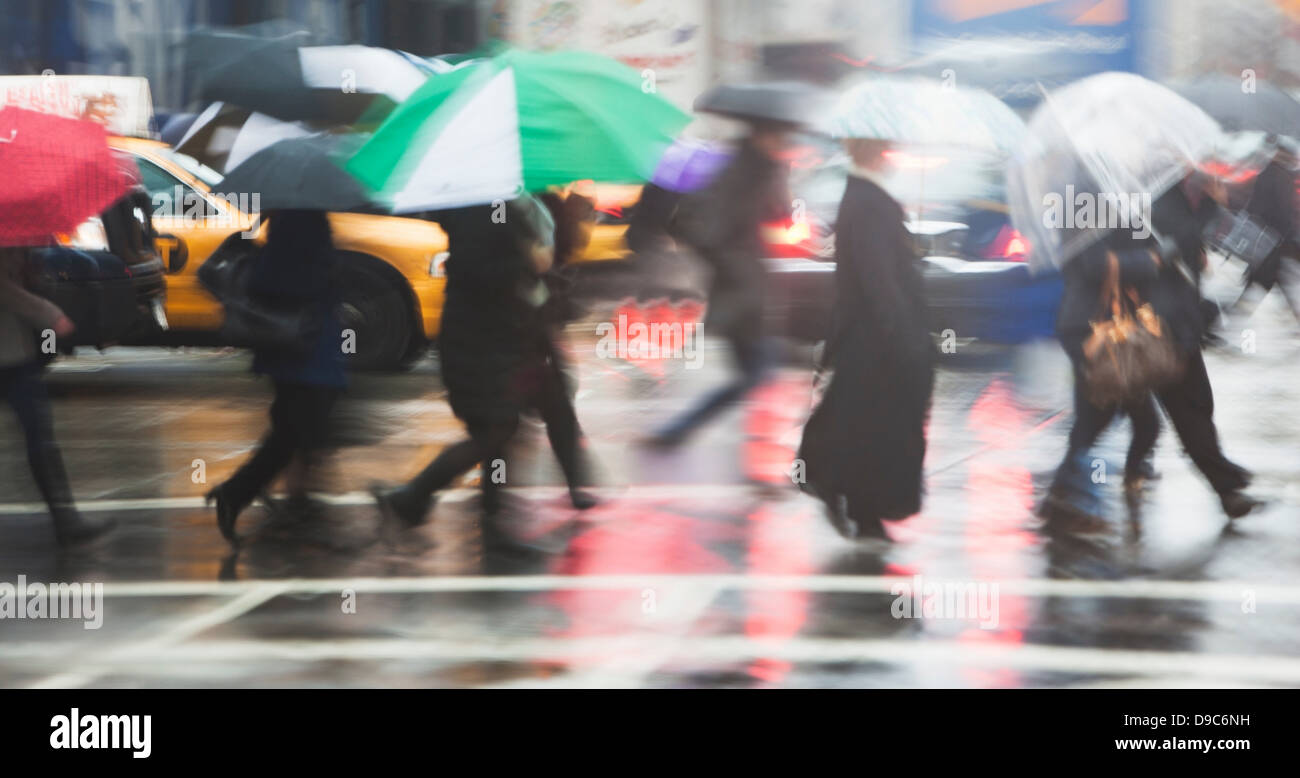 Linie von Menschen Kreuzung Stadtstraße in Regen Stockfoto
