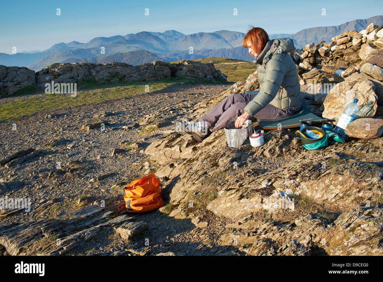 Ein Wanderer, Kochen auf einem Campingkocher auf dem Gipfel des Robinson im Lake District. Stockfoto