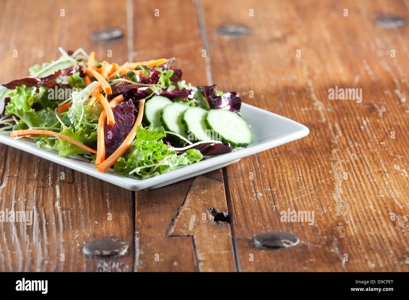 Quadratische weiße Schüssel mit bunten frisch und Bio-Rucola-Salat garniert mit einem Sortiment von knackigem Gemüse. Stockfoto