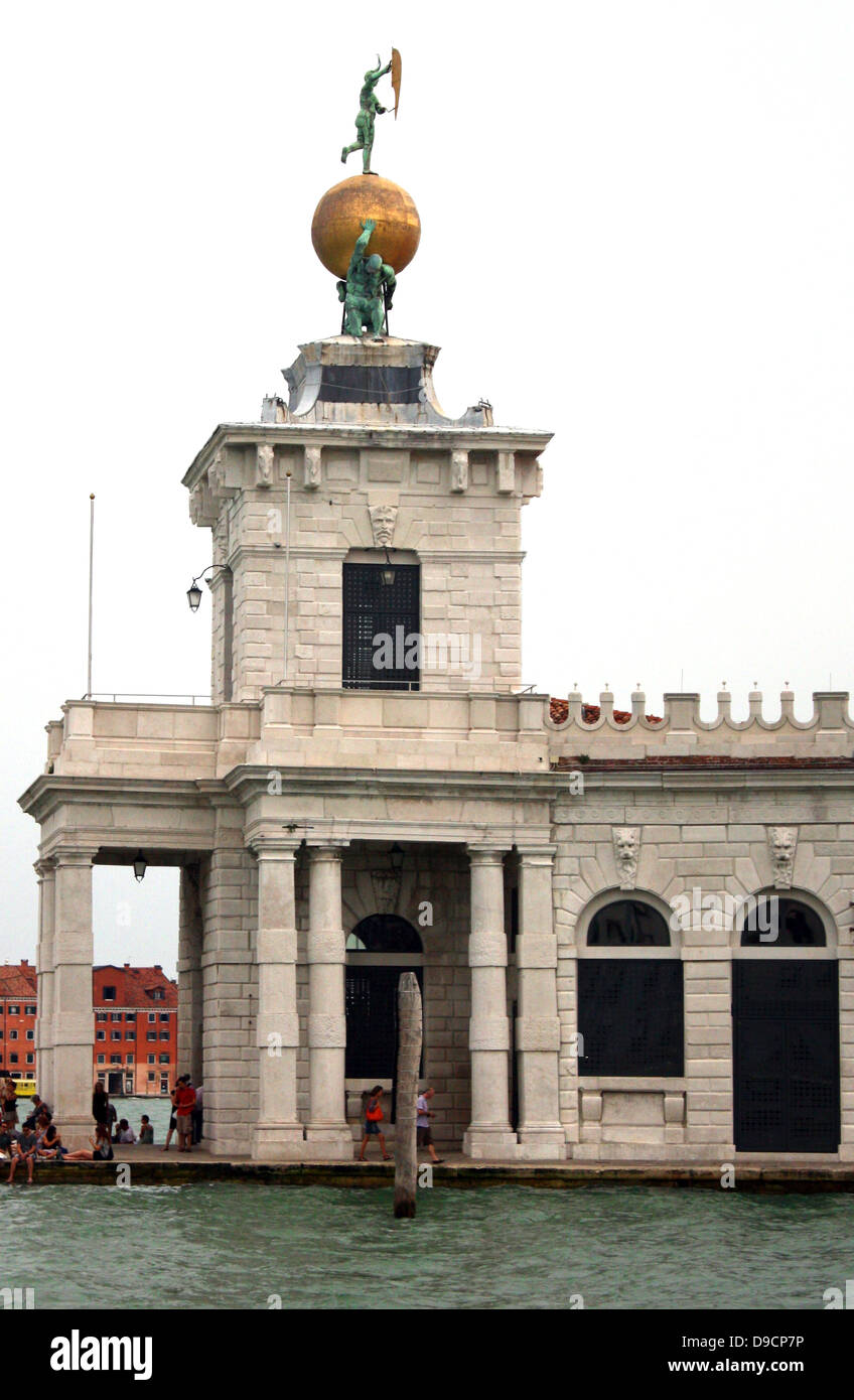 Dreieckigen Punta della Dogana, (das ehemalige Zollhaus der Stadt) trennt den Grand Canal und der Canale della Giudecca in Venedig, Italien. Heute ist es ein Zentrum für zeitgenössische Kunst im 17. Jahrhundert. Der Turm halten sie eine goldene Kugel, das von zwei Atlanten unterstützt wird; diese Statue stellt Vermögen. Es wurde von Bernardo Falconi geformt Stockfoto