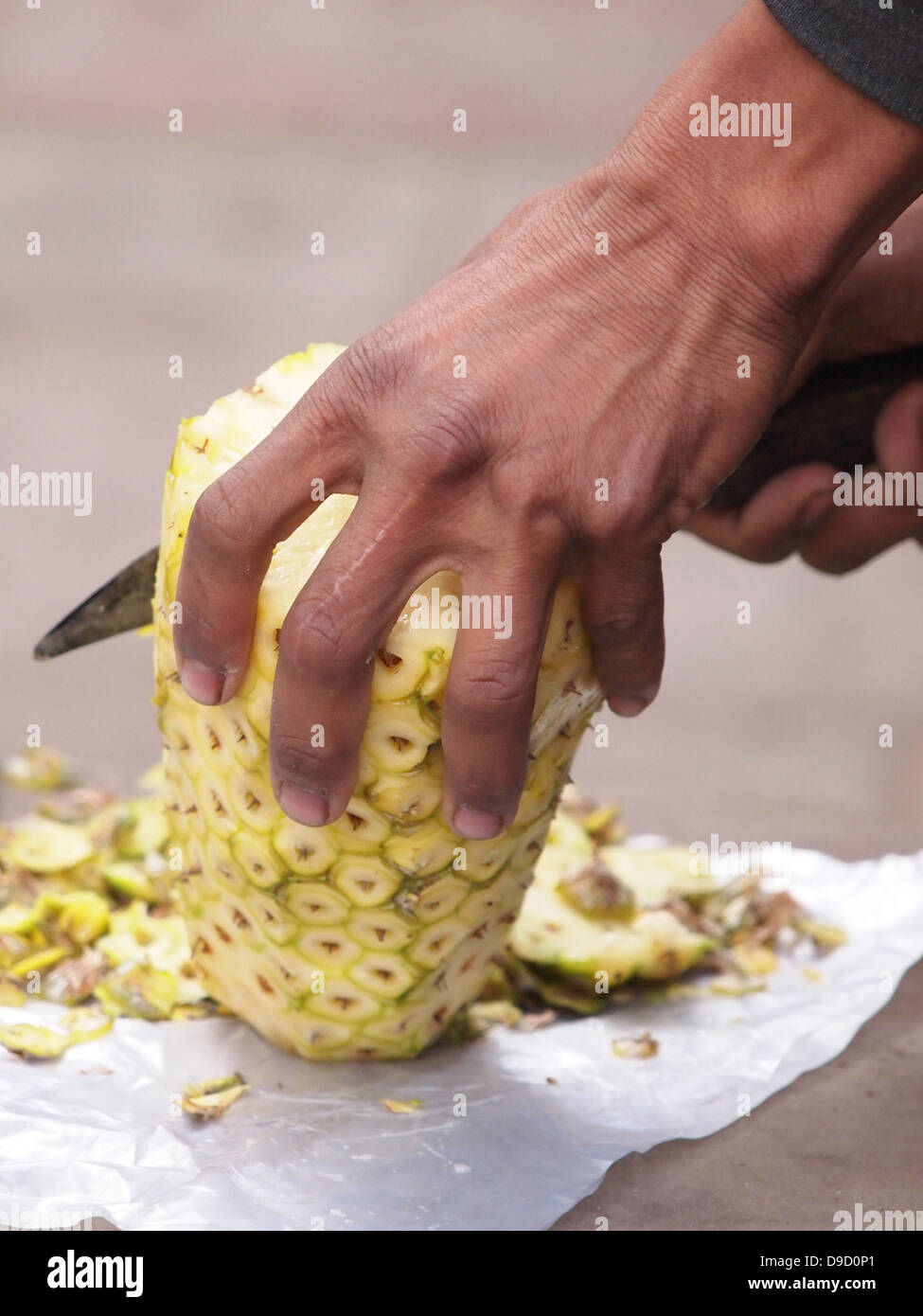 Blick auf eine asiatische Frau, die eine Ananas aufschneiden, mit einem Messer abgeschnitten Stockfoto