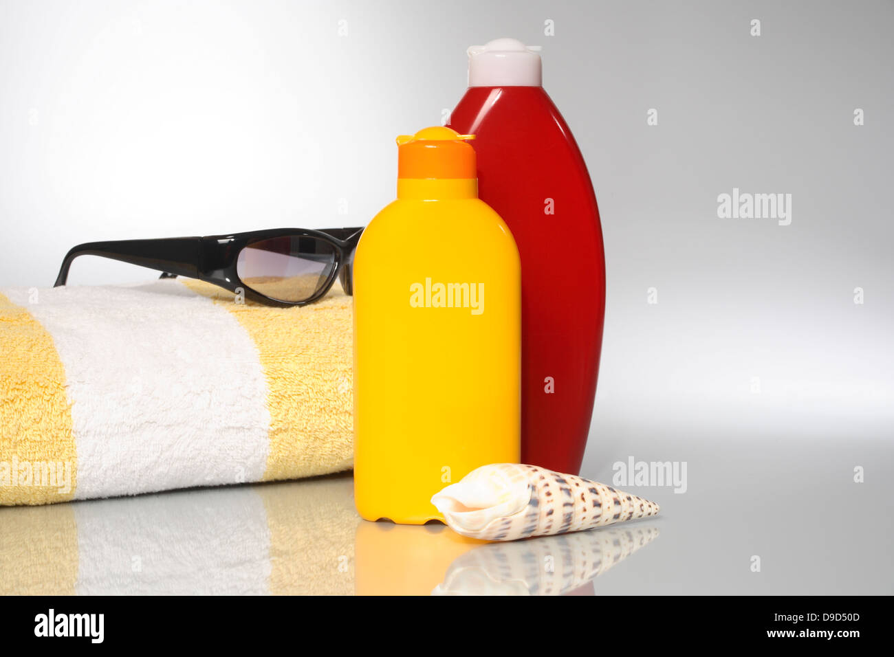 Sonnenlotion mit Handtuch und Sonnenbrillen Stockfoto