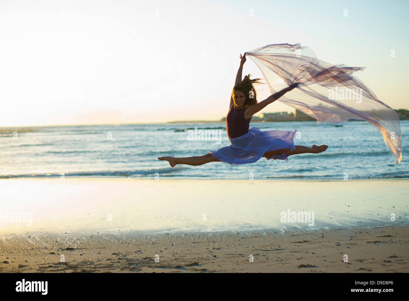 Junge Frau am sonnigen Strand tanzen Stockfoto