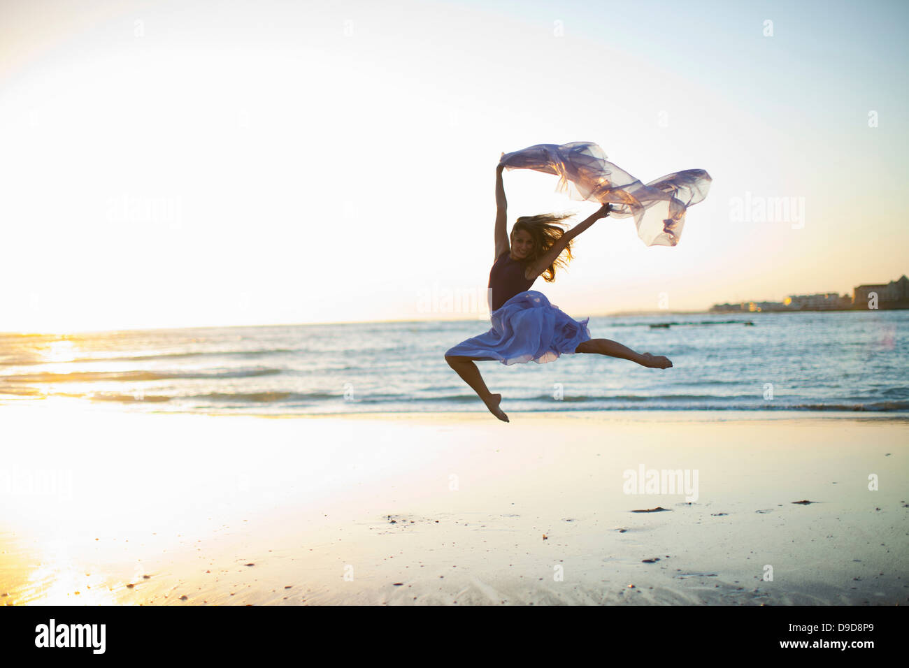 Junge Frau am sonnigen Strand tanzen Stockfoto