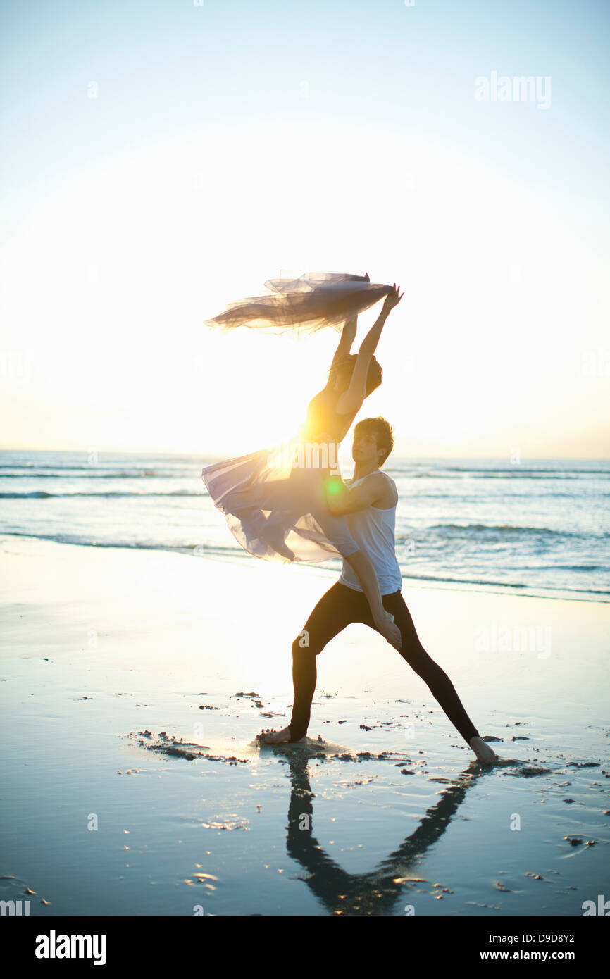 Junger Mann heben Tanzpartner am sonnigen Strand Stockfoto