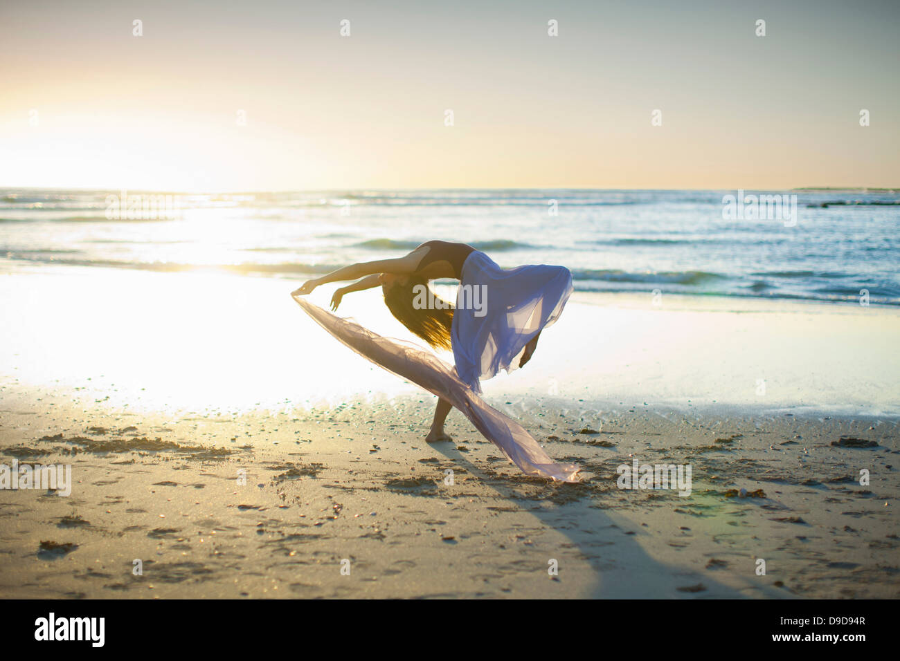 Junge Frau am sonnigen Strand tanzen Stockfoto