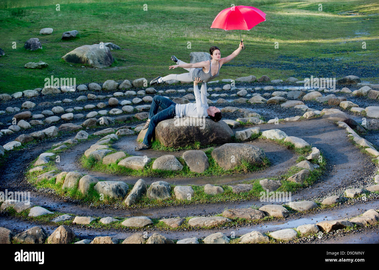 Mitte Erwachsenen Tänzerinnen mit roten Sonnenschirmen im Steinkreis Stockfoto