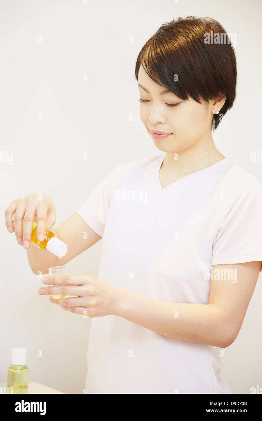 Frau Aromatherapie Öl in den Behälter gießen Stockfoto