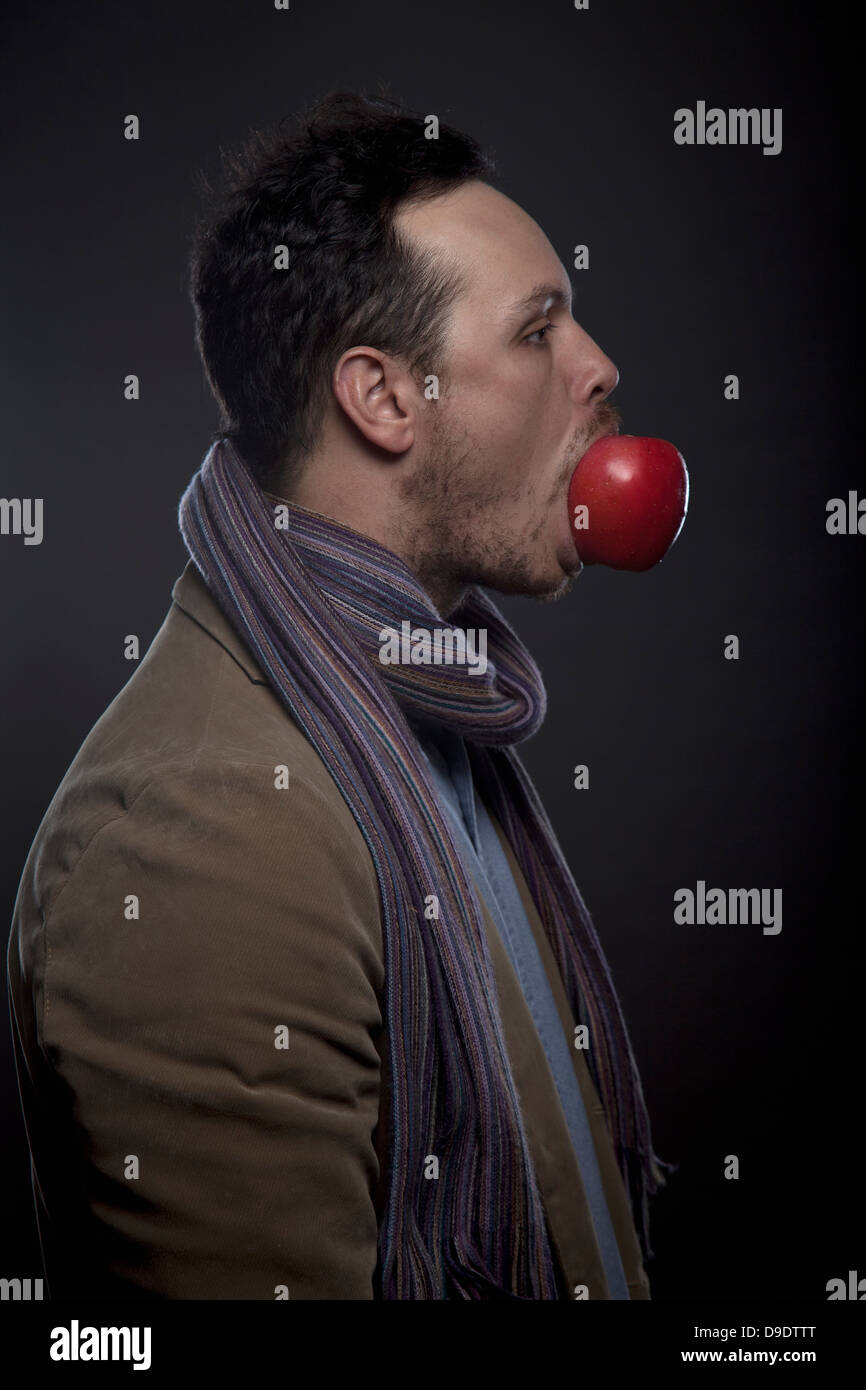 Porträt des Mannes mit Apfel im Mund Stockfoto