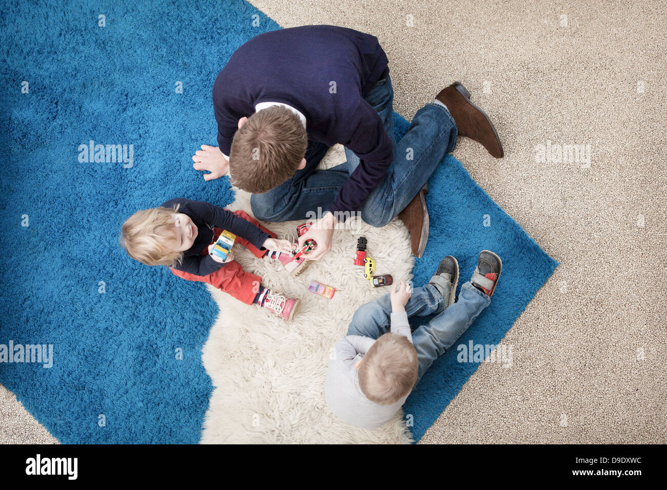 Vater mit Sohn und Tochter auf Sofa mit Spielzeugautos spielen Stockfoto